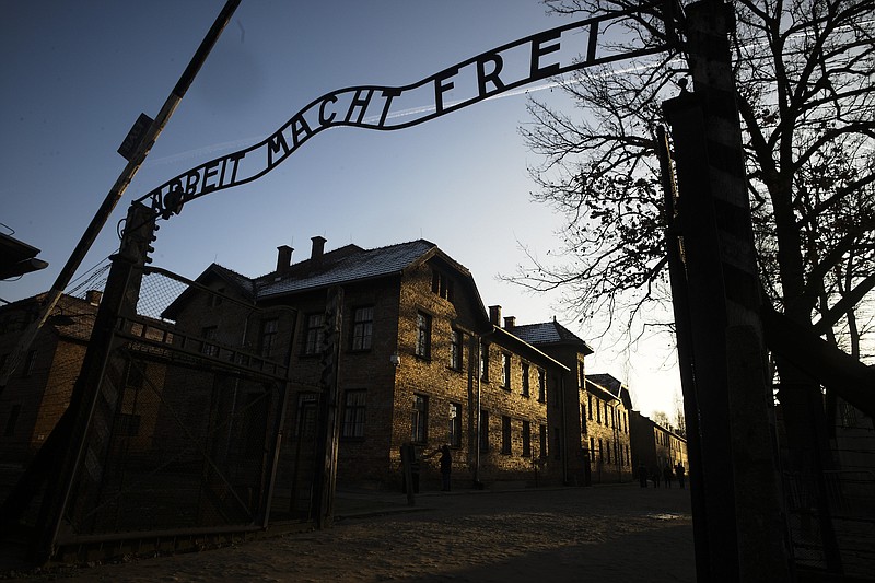 File photo by Markus Schreiber of The Associated Press / In this Dec. 6, 2019 photo, the sun lights the buildings behind the entrance of the former Nazi death camp of Auschwitz-Birkenau in Oswiecim, Poland.