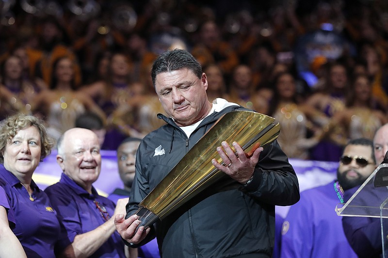 LSU football coach Ed Orgeron holds the College Football Playoff's national championship trophy during an on-campus celebration of the team's 15-0 season last Saturday in Baton Rouge, La. / AP photo by Gerald Herbert