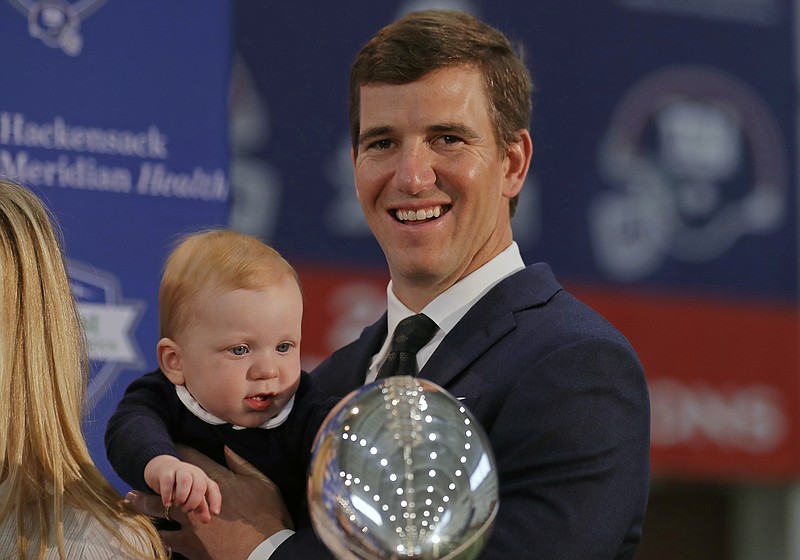 Eli Manning holds his son Charles after a news conference Friday in East Rutherford, N.J. Manning has retired after 16 seasons as quarterback of the New York Giants. / AP photo by Adam Hunger