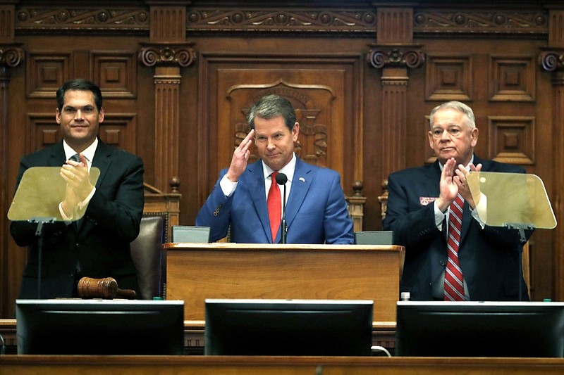 FILE - In this Jan. 16, 2020 file photo, Gov. Brian Kemp, center, is flanked by House Speaker David Ralston, R-Blue Ridge, right, and Lt. Gov. Geoff Duncan as he salutes former U.S. Senator Johnny Isakson, R-Ga., during the State of the State address before a joint session of the Georgia General Assembly in Atlanta. Kemp is proposing that Georgia borrow almost $900 million for construction projects and equipment next year. Key projects in the Republican governor's borrowing plan include $70 million to expand the state-owned convention center in Savannah and $55 million to build a new headquarters for the Department of Public Safety in Atlanta. (AP Photo/John Bazemore, File)