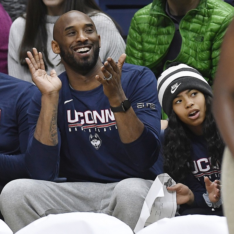 Kobe Bryant and his daughter Gianna watch the first half of a college basketball game between Houston and Connecticut on March 2, 2019, in Storrs, Conn. Both were killed in a helicopter crash in the Los Angeles area on Sunday, Jan. 26, 2020. / AP photo by Jessica Hill