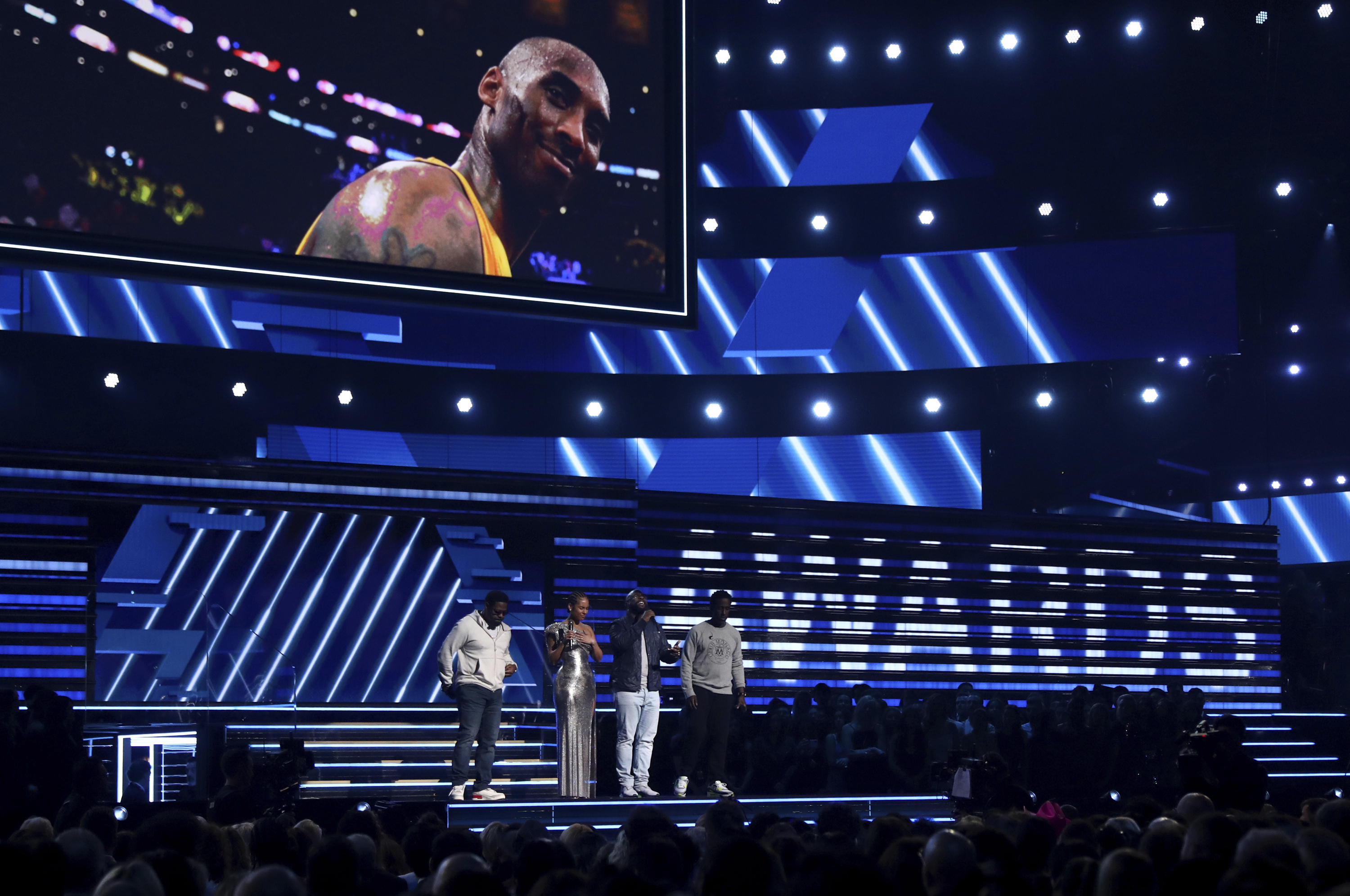 From left, Nathan Morris, Alicia Keys, Wanya Morris and Shawn Stockman sing a tribute in honor of the late Kobe Bryant, seen on screen, at the 62nd annual Grammy Awards on Sunday in Los Angeles. The Boyz II Men members joined Keys, who hosted the ceremony that took place just hours after Bryant's death in a helicopter crash in the Los Angeles area. / Invision photo by Matt Sayles via AP