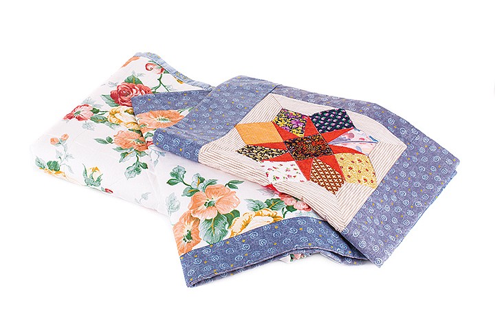 Stack of beautiful handmade quilts. It is isolated in a white background. Close-up.