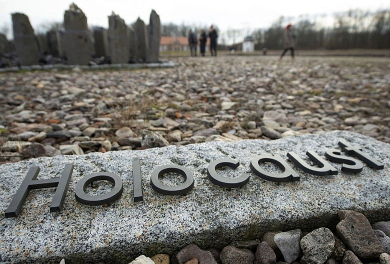 People walk behind the writing 'Holocaust' during the international Holocaust remembrance day in the former the Nazi concentration camp Buchenwald near Weimar, Germany, Monday, Jan. 27, 2020. January 27 is the date in 1945 on which the Soviet army liberated the largest Nazi death camp at Auschwitz-Birkenau, Poland, where more than 1 million prisoners were killed. (AP Photo/Jens Meyer)