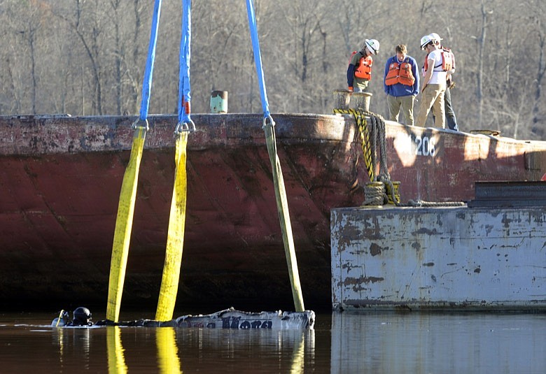 A diver works in the water as a crane attempts to lift the remains of a burned boat in Scottsboro, Ala., on Tuesday, Jan. 28, 2020, following a dock fire that killed eight people. Sunken in a creek that feeds into the Tennessee River, officials said the craft was one of about 35 that were engulfed in flames. (AP Photo/Jay Reeves)