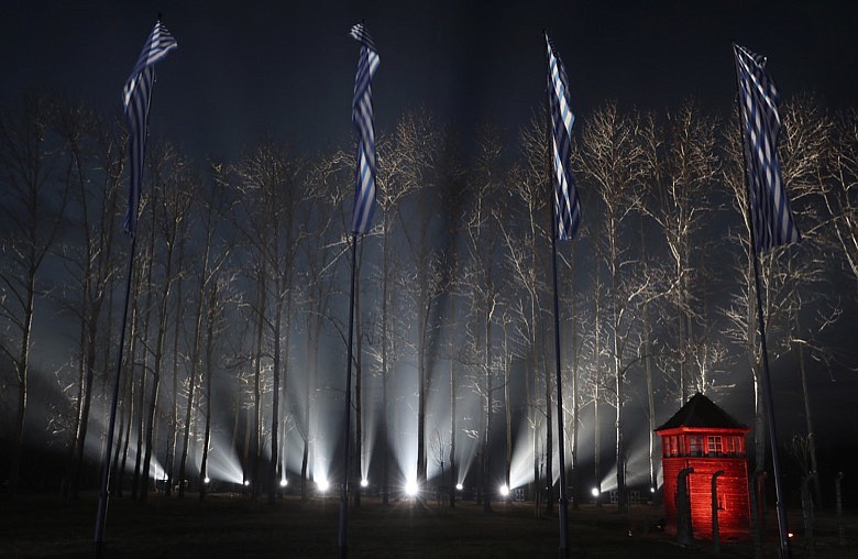 Flags with the stripes of the prison uniforms of Nazi death camps fly at the fence of Birkenau at the Auschwitz Nazi death camp in Oswiecim, Poland, Monday, Jan. 27, 2020. Survivors of the Auschwitz-Birkenau death camp gathered for commemorations marking the 75th anniversary of the Soviet army's liberation of the camp, using the testimony of survivors to warn about the signs of rising anti-Semitism and hatred in the world today. (AP Photo/Czarek Sokolowski)