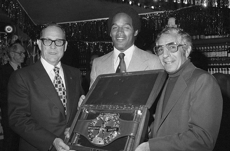 O.J. Simpson, Buffalo Bills running back, receives the S. Rae Hickock Professional Athlete of the Year award at a ceremony in New York, Feb. 4, 1974. At right is Phil Rizzuto, who was the first recipient of the award in 1950. Simpson is the fourth football player to receive the award and a diamond studded gold-buckled belt worth more than $15,000. (AP Photo/Dave Pickoff)