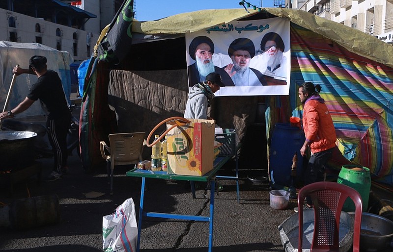 Free food is prepared for protesters during the ongoing anti-government protests next to a poster of Muqtada al-Sadr whose image is centered between the image of his father, Ayatollah Mohammed Sadiq al-Sadr, right, and Shiite spiritual leader Grand Ayatollah Ali al-Sistani, left, in Tahrir Square in Baghdad, Iraq, Saturday, Feb. 1, 2020. (AP Photo/Khalid Mohammed)

