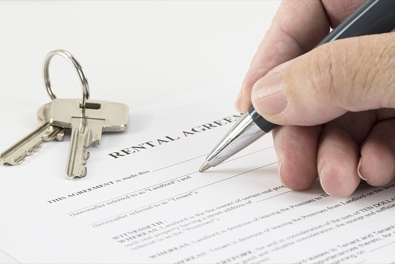 Signing a rental agreement document, house keys in the background. / Getty Images/iStockphoto/fermate