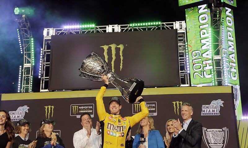 FILE - In this Nov. 17, 2019, file photo, Kyle Busch, center, holds up his trophy in Victory Lane after winning a NASCAR Cup Series auto racing season championship at Homestead-Miami Speedway in Homestead, Fla. NASCAR's season officially opens Sunday, Feb. 16, 2020, with the Daytona 500 at Daytona International Speedway. (AP Photo/Terry Renna, File)