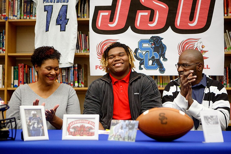 Flanked by his parents, Rhonda Dodds and Ron Key, Malcolm Key smiles during Wednesday's ceremony in the library at Sale Creek Middle/High School to celebrate the 6-foot-8, 360-pound lineman signing a football scholarship with Jacksonville State. / Staff photo by C.B. Schmelter