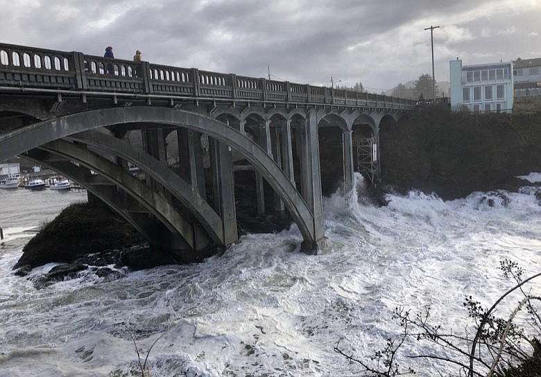 In this Jan. 11, 2020 photo heavy surf surrounds the legs of a bridge as an extreme high tide rolls into the harbor in Depoe Bay, Ore. during a so-called "king tide" that coincided with a big winter storm. Amateur scientists are whipping out their smartphones to document the effects of extreme high tides on shore lines from the United States to New Zealand, and by doing so are helping better predict what rising sea levels due to climate change will mean for coastal communities around the world. (AP Photo/Gillian Flaccus)