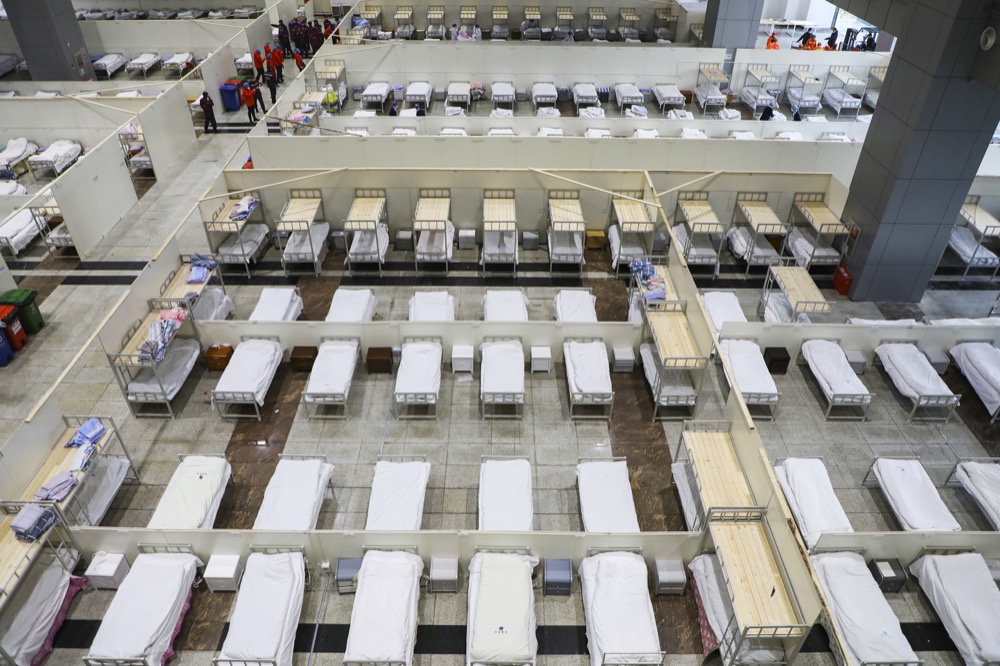 In this Wednesday, Feb. 5, 2020, photo, medical staff prepare beds at a temporary hospital which transformed from an exhibition center for accepting patients who diagnosed with the coronaviruses in Wuhan in central China's Hubei province. Ten more people were sickened with a new virus aboard one of two quarantined cruise ships with some 5,400 passengers and crew aboard, health officials in Japan said Thursday, as China reported 73 more deaths and announced that the first group of patients were expected to start taking a new antiviral drug. (Chinatopix via AP)