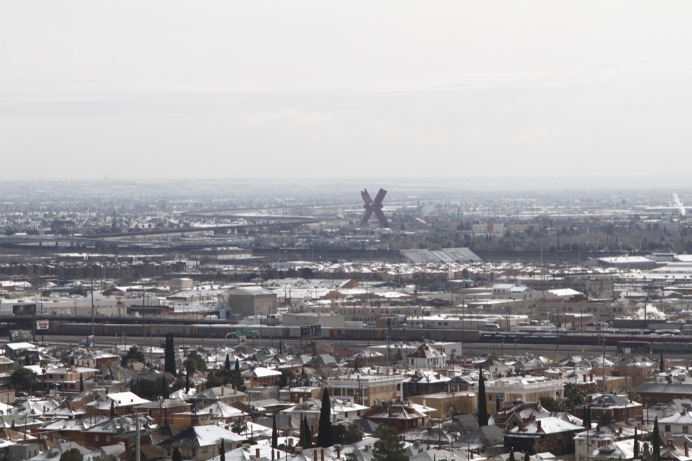 Snow covers rooftops on either side of the U.S.-Mexico border as seen on Wednesday, Feb. 5, 2020, from El Paso, Texas. A few inches of snow led to slow starts at schools in El Paso and caused hour-long delays on local roads. The fence marking the border can be seen in the upper half of the photo. The red "X"-shaped building is in Ciudad Juarez, Mexico. (AP Photo/Cedar Attanasio)