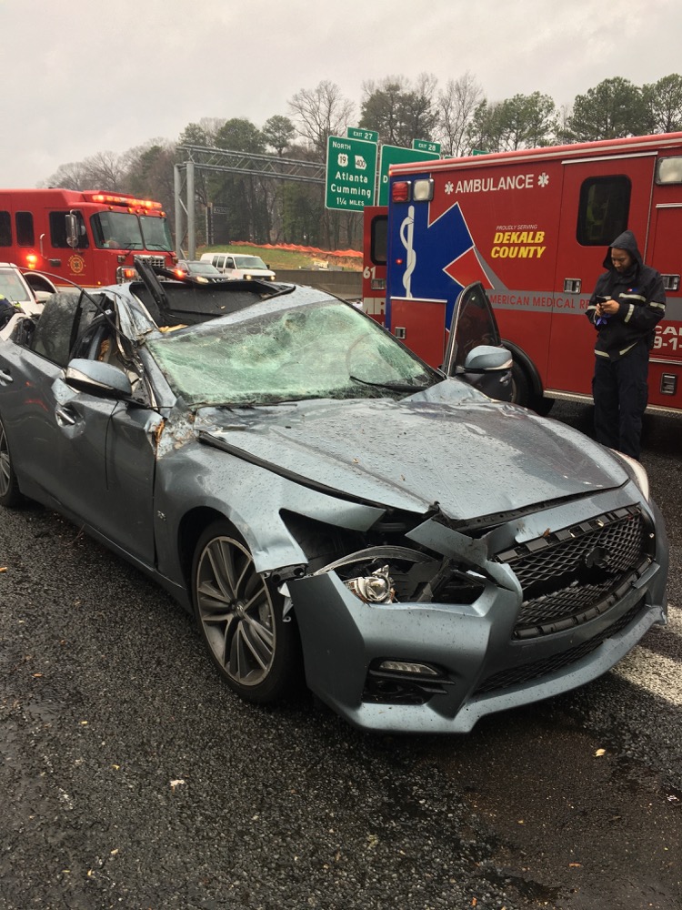 In this image made available by the Dunwoody Police Dept. rescue personnel inspect a car that was damaged by a falling tree on Interstate 285, Thursday, Feb. 6, 2020 in Dunwoody, Ga. No injuries were reported. A powerful winter storm brought severe weather across the Deep South early Thursday, with high winds causing damage that killed at least one person, injured several others and littered at least four states. (Dunwoody Police Dept. via AP)