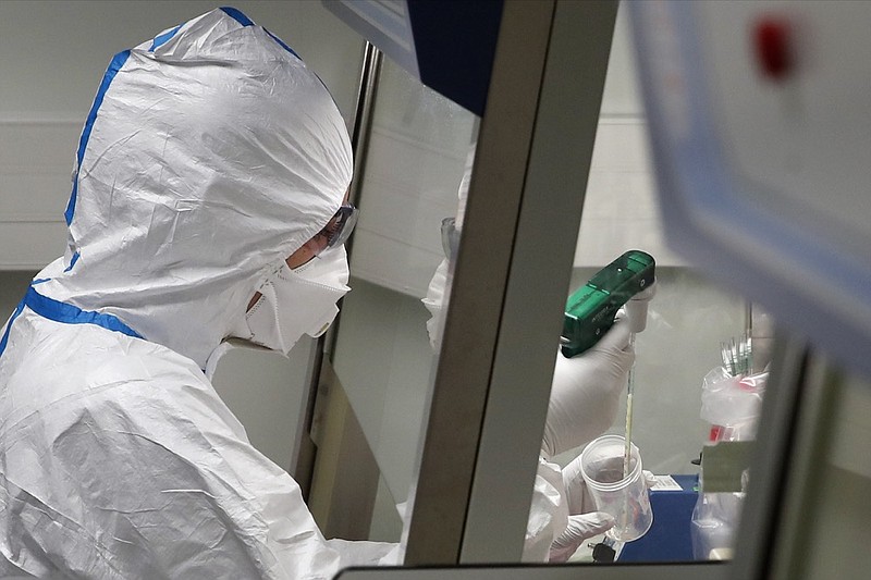 A French lab scientist in hazmat gear is seen inserting liquid in test tube manipulates potentially infected patient samples at Pasteur Institute in Paris, Thursday, Feb. 6, 2020. Scientists at the Pasteur Institute developed and shared a quick test for the new virus that is spreading worldwide, and are using genetic information about the coronavirus to develop a potential vaccine and treatments. (AP Photo/Francois Mori)

