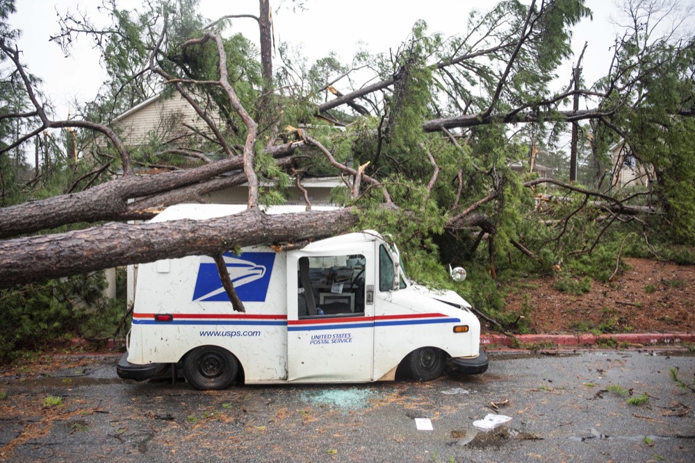 Fallen trees rest on a damaged postal truck at an apartment complex where a reported tornado passed through Thursday, Feb. 6, 2020, in Spartanburg, S.C. A powerful winter storm brought severe weather across the Deep South early Thursday, with high winds causing damage that killed one person, injured several others and littered at least four states. (AP Photo/Sean Rayford)