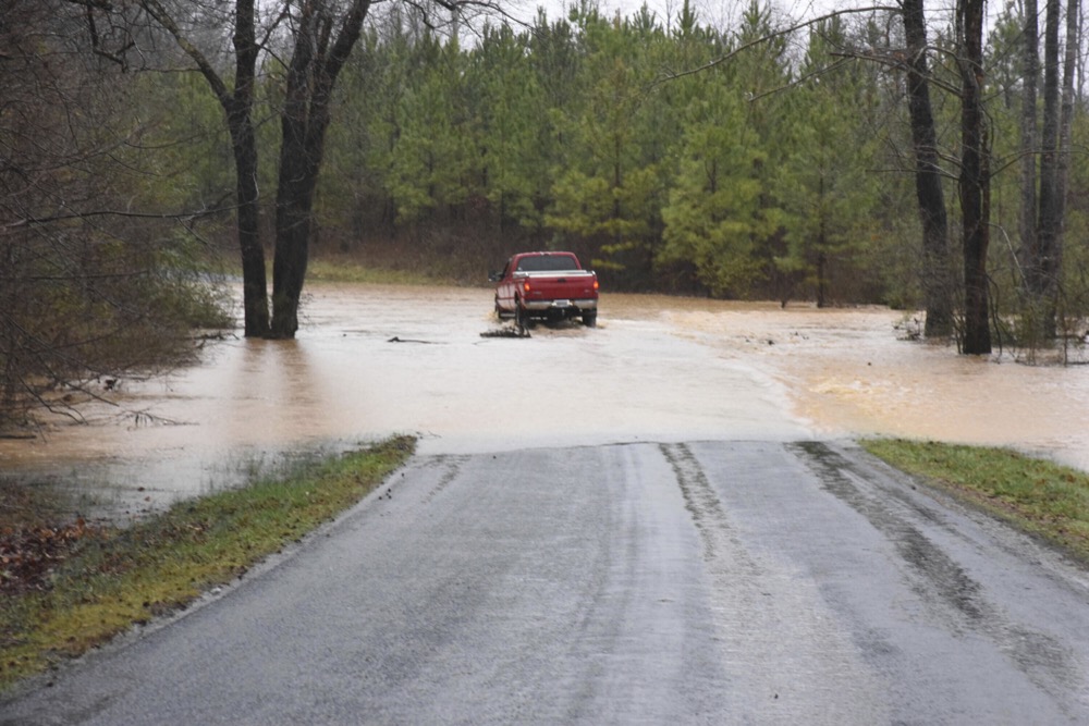 A truck drives through a pool of water on Thursday, Feb. 6, 2020, on Sandy Creek Road in Pittsylvania County, Va., which had several areas of moving water that rose as high as a few feet. (Caleb Ayers/Danville Register & Bee via AP)