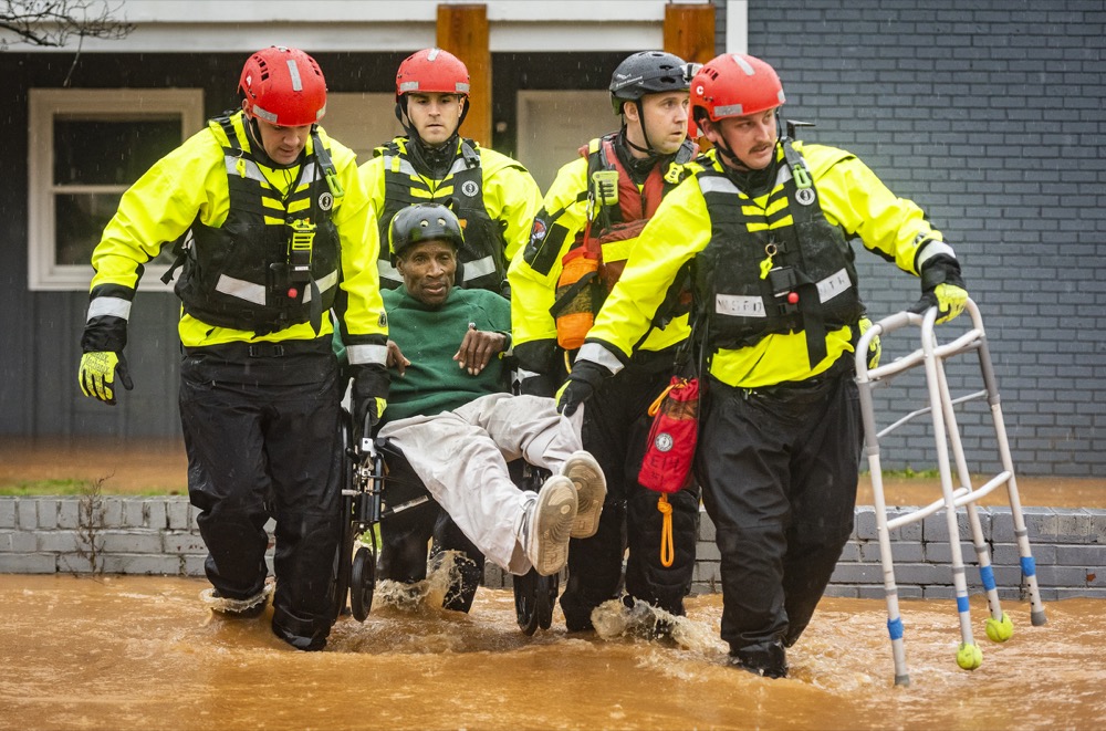 Winston-Salem Fire Department firefighters with the Rescue Task Force rescue James Benjamin from his home at Liberty Landing Apartments as flood waters rise around the building on Thursday, Feb. 6, 2020, in Winston-Salem, N.C. (Andrew Dye/The Winston-Salem Journal via AP)