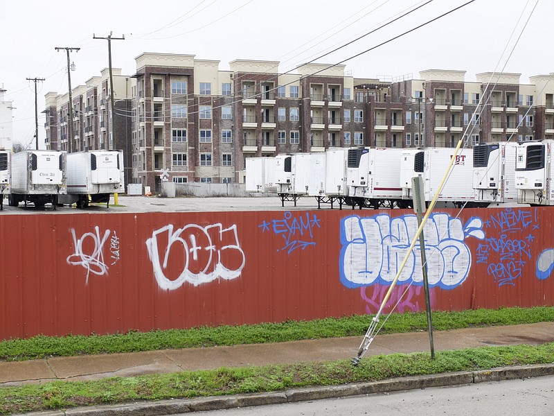 Staff photo by Tim Barber/ In this view from the 1600 block of Chestnut Strreet, graffiti is seen on a red fence separating the Pilgrim's Pride chicken plant from the sidewalk. Refridgerated trailers sit on the parking lot in front of the nearby Broad Street apartment complex where pre-leasing is set to start soon.