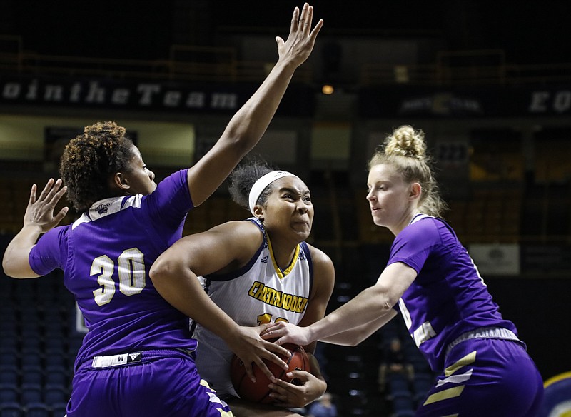 Staff photo by Troy Stolt / UTC forward Bria Dial drives to the basket between Western Carolina's Jewel Smalls, left, and Alyssa Walker during Saturday's game at McKenzie Arena.