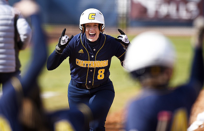 Staff photo by Robin Rudd / UTC's Katie Corum celebrates her home run as her teammates wait to greet her at home plate during the first inning of Sunday's season opener against Austin Peay at Frost Stadium. UTC won 9-1 before losing the second game of the doubleheader 4-1.