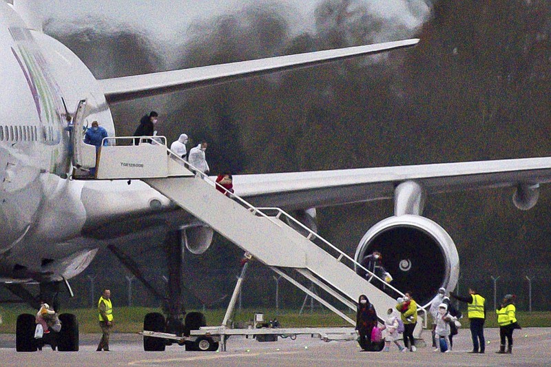 People wearing face masks disembark from an aircraft repatriating British and other nationalities to the UK from the coronavirus hit city of Wuhan in China, following its arrival at RAF Brize Norton, England, Sunday Feb. 9, 2020. (Jacob King/PA via AP)