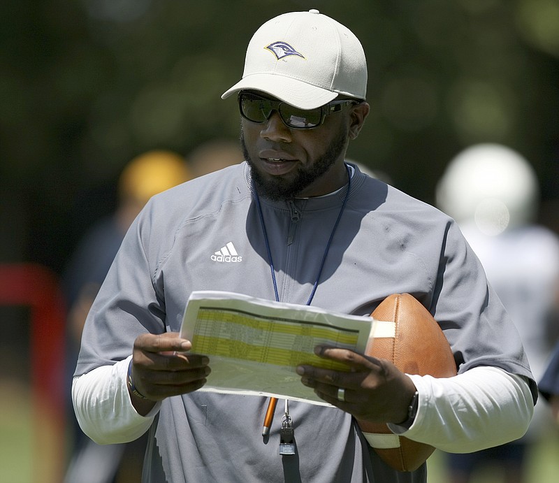 Staff photo by C.B. Schmelter /  UTC outside linebackers coach Shelton Felton checks a sheet during the first day of fall practice at Scrappy Moore Field on Monday, July 24, in Chattanooga, Tenn
