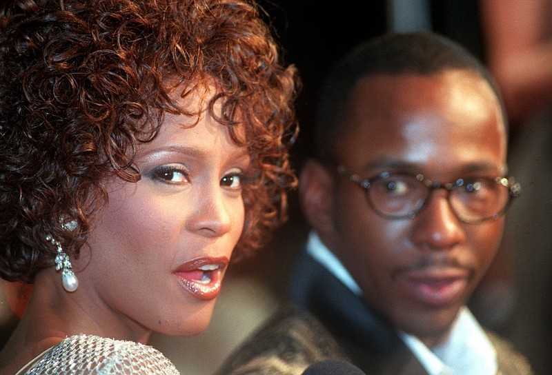 FILE - In this Oct. 13, 1997 file photo, Whitney Houston looks over her shoulder as her husband Bobby Brown looks to her at the premiere of "The Wonderful World of Disney" movie "Cinderella," at Mann's Chinese Theater in the Hollywood section of Los Angeles, Whitney Houston, who reigned as pop music's queen until her majestic voice and regal image were ravaged by drug use, has died, Saturday, Feb. 11, 2012. She was 48. (AP Photo/Rene Macura, File)