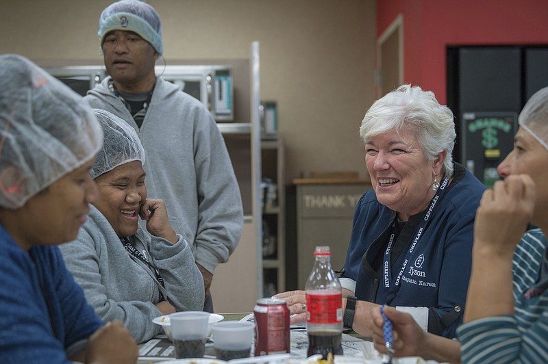 In this October 2018 photo provided by Tyson Foods, Karen Diefendorf, second right, director of Chaplain Services at Tyson Foods, talks with employees at the company's Berry St. poultry plant in Springdale, Ark. The company deploys a team of more than 90 chaplains to comfort and counsel employees at its plants and offices. The program began in 2000. (Logan Webster/Tyson Foods via AP)