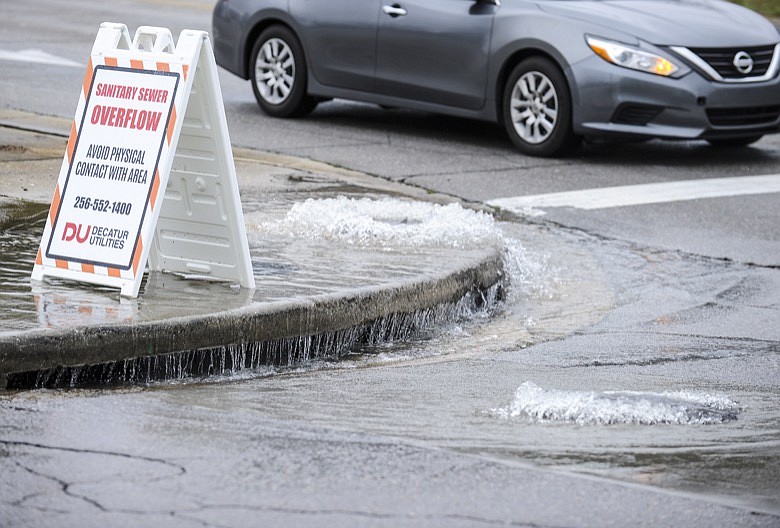 Untreated sewage overflows from two manholes, one on the sidewalk of Central Parkway, left, and the other on 2nd Street Southwest in Decatur, Ala. on Tuesday, February 11, 2020. (Jeronimo Nisa/The Decatur Daily via AP)