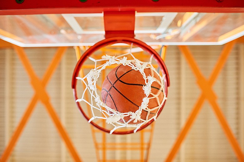 From below, shot of basketball ball falling through net, basket, hoop in gym. / Getty Images/iStockphoto/SeventyFour