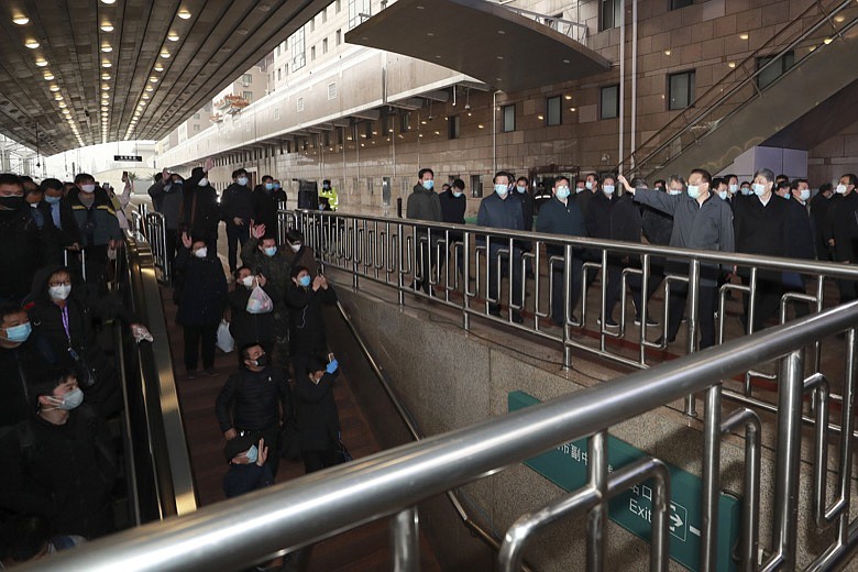 In this Friday, Feb. 14, 2020, photo released by China's Xinhua News Agency, Chinese Premier Li Keqiang, waving at right, greets travelers arriving at Beijing West Railway Station in Beijing. China reported Saturday a figure of 2,641 new virus cases, a major drop from the higher numbers in recent days since a broader diagnostic method was implemented. (Ding Lin/Xinhua via AP)