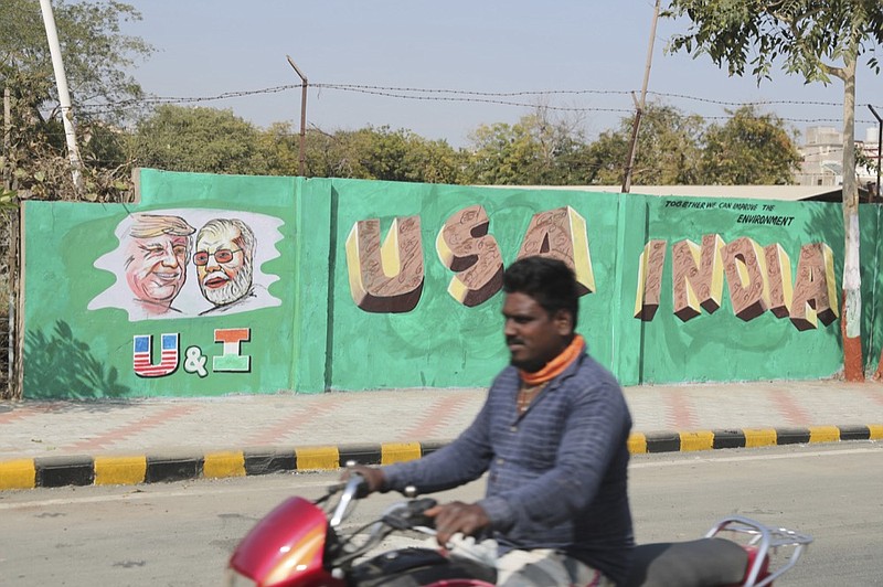 A man rides past a wall painted with portraits of U.S. President Donald Trump and Indian Prime Minister Narendra Modi ahead of Trump's visit, in Ahmadabad, India, Tuesday, Feb. 18, 2020. Trump is scheduled to visit the city during his Feb. 24-25 India trip. (AP Photo/Ajit Solanki)

