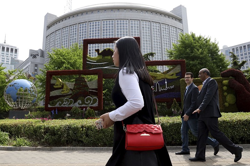 In this April 19, 2019, photo, foreigners pass by the Chinese Foreign Ministry in Beijing, China. China on Wednesday, Feb. 19, 2020 said it has revoked the press credentials of three reporters for the U.S. newspaper Wall Street Journal over a headline for an opinion column deemed by the government to be racist and slanderous. (AP Photo/Ng Han Guan)


