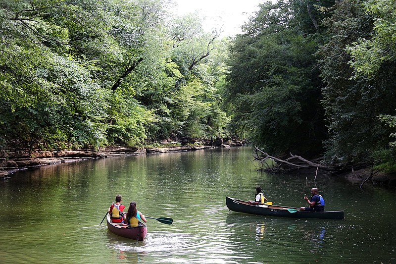 Staff file photo by Erin O. Smith / Isaiah, Leilah and Jessica Franklin, in the canoe on the left, and Timothy and Elijah Franklin, in the boat on the right, canoe down North Chickamauga Creek during Family Fun Day at Greenway Farm City Park.