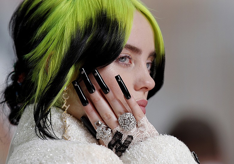 In this Sunday, Feb. 9, 2020 file photo Billie Eilish arrives at the Oscars at the Dolby Theatre in Los Angeles. Singer-songwriter Lewis Capaldi and rapper Dave lead the nominations for the U.K. music industry's Brit Awards, set to be handed out Tuesday Feb. 18, 2020, at a ceremony in London. Quintuple Grammy winner Billie Eilish, 18, is set to give the first public performance of her James Bond theme song "No Time to Die." (AP Photo/John Locher, File)