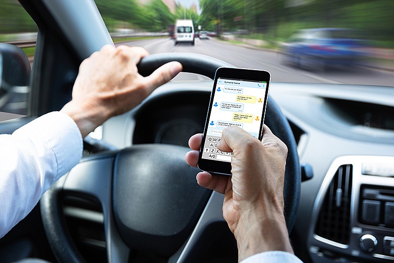 Man typing text message on mobile phone while driving car. / Getty Images/iStockphoto/AndreyPopov 