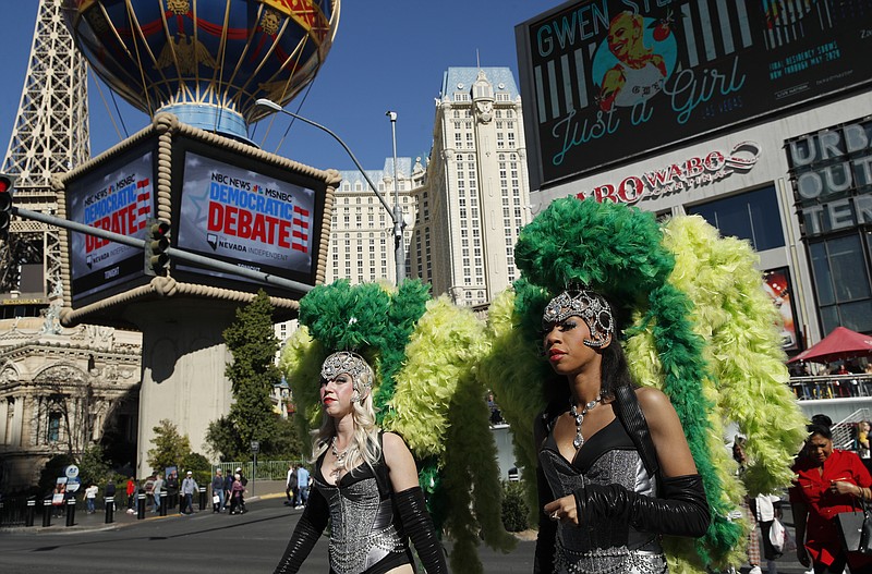 FILE - In this Feb. 19, 2020, file photo, people dressed as showgirls walk near the Paris Las Vegas hotel casino, site of a Democratic presidential debate in Las Vegas. Just past the roulette wheel and slot machines, the smoky bars and blinking lights, Nevada Democrats are preparing to weigh in on their party's presidential nomination fight. (AP Photo/John Locher, File)