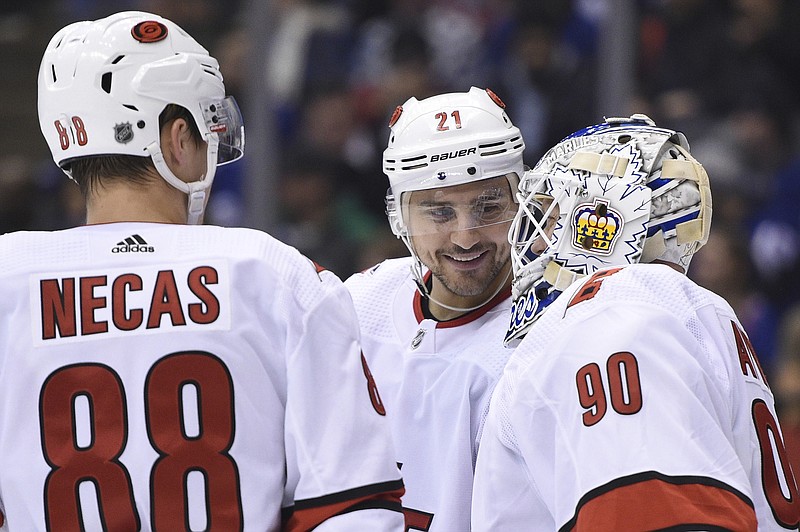 The Canadian Press photo by Frank Gunn via AP / Carolina Hurricanes right wing Nino Niederreiter, center, and center Martin Necas speak to emergency goalie David Ayres as he takes the ice against the Toronto Maple Leafs during the second period of Saturday's game in Toronto.