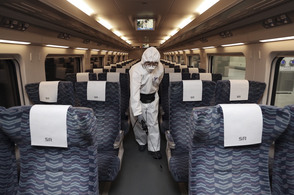 A worker wearing protective gears sprays disinfectant as a precaution on a train against the new coronavirus at Suseo Railway Station in Seoul, South Korea, Tuesday, Feb. 25, 2020. China and South Korea on Tuesday reported more cases of a new viral illness that has been concentrated in North Asia but is causing global worry as clusters grow in the Middle East and Europe. (Lee Ji-eun/Yonhap via AP)