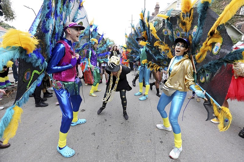 Dressed as peacocks, a group of friends calling themselves "The Ostentation" form a dance line for revelers in the Society of St. Anne on Royal Street in New Orleans, Tuesday, Feb. 25, 2020. (AP Photo/Rusty Costanza)