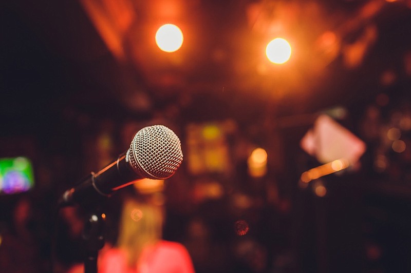 Microphone on stage against a background of auditorium. - stock photo comedy tile show tile performance perform comedian auditorium stage tile / Getty Images
