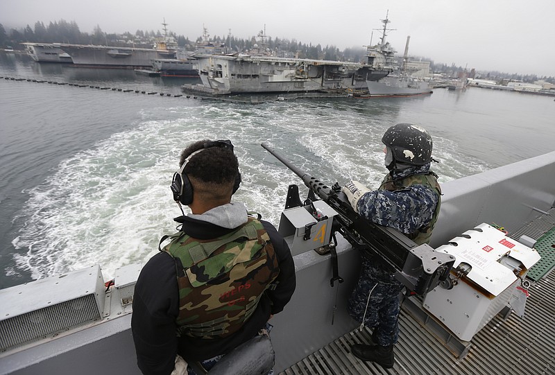 FILE - In this Jan. 13, 2015, file photo, two sailors stand with a gun as the USS John Stennis aircraft carrier leaves Naval Base Kitsap in Washington state. A federal judge in Seattle ruled Thursday, Feb. 27, 2020, that President Donald Trump cannot divert $89 million intended for a construction project at the base to help build his wall on the U.S.-Mexico border. (AP Photo/Ted S. Warren, File)