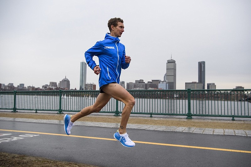Hoka One One photo via AP / Tyler Andrews runs along the Charles River in Cambridge, Mass., with the Boston skyline in the background on March 29, 2019. Andrews isn't among the favorites at the Olympic Marathon trials this weekend in Atlanta, but don't be surprised if he makes a run at a spot on the U.S. team for this summer's Tokyo Games.