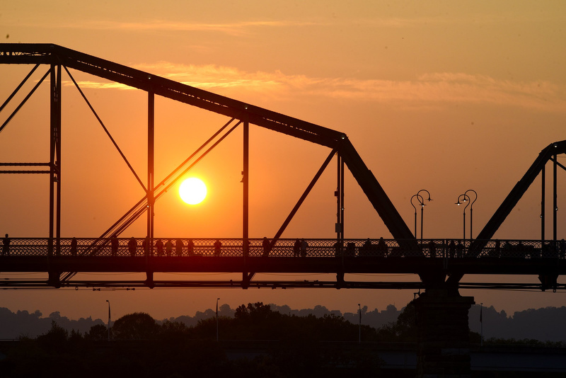 Staff Photo by Robin Rudd/ The sun rises behind the Walnut Street Bridge as spectators watch the swimming segment of the The Little Debbie Ironman. The Little Debbie Ironman Chattanooga took place under hot conditions on September 29, 2019.