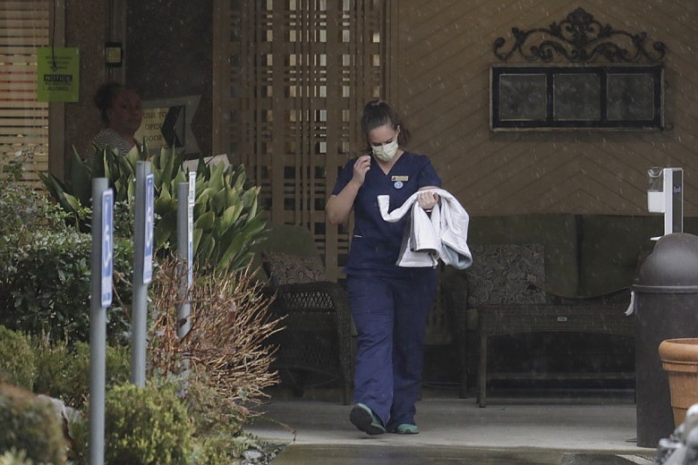 A worker at the Life Care Center in Kirkland, Wash., near Seattle, wears a mask as she leaves the building, Monday, March 2, 2020. Several of the people who have died in Washington state from the COVID-19 coronavirus were tied to the long-term care facility, where dozens of residents were sick. (AP Photo/Ted S. Warren)