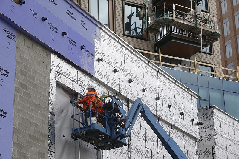 FILE - In this Nov. 27, 2019 file photo workers use a lift while working on a new building in Boston's Seaport district. Spending on U.S. construction projects rose to an all-time high in January, helped by strong gains for home construction and government building projects. The Commerce Department said Monday, March 2, 2020, that construction spending increased 1.8% in January, the strongest monthly rise in nearly two years, pushing totally spending to a record seasonally adjusted annual rate of $1.37 trillion.  (AP Photo/Steven Senne, File)