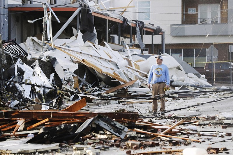 A man looks over buildings destroyed by storms Tuesday, March 3, 2020, in Nashville, Tenn. At least two tornadoes touched down early Tuesday in central Tennessee, including one that ripped across areas near downtown Nashville and caused multiple buildings to collapse. (AP Photo/Mark Humphrey)
