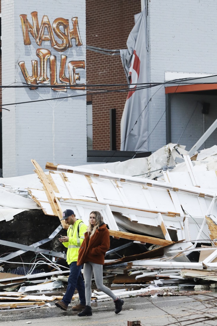 People walk past storm debris following a deadly tornado, Tuesday, March 3, 2020, in Nashville, Tenn. Tornadoes ripped across Tennessee early Tuesday, shredding buildings and killing multiple people. (AP Photo/Mark Humphrey)